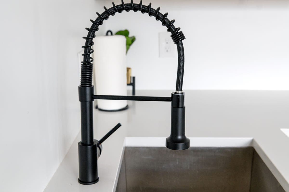 Kitchen faucet spray hose extended over a sink basin